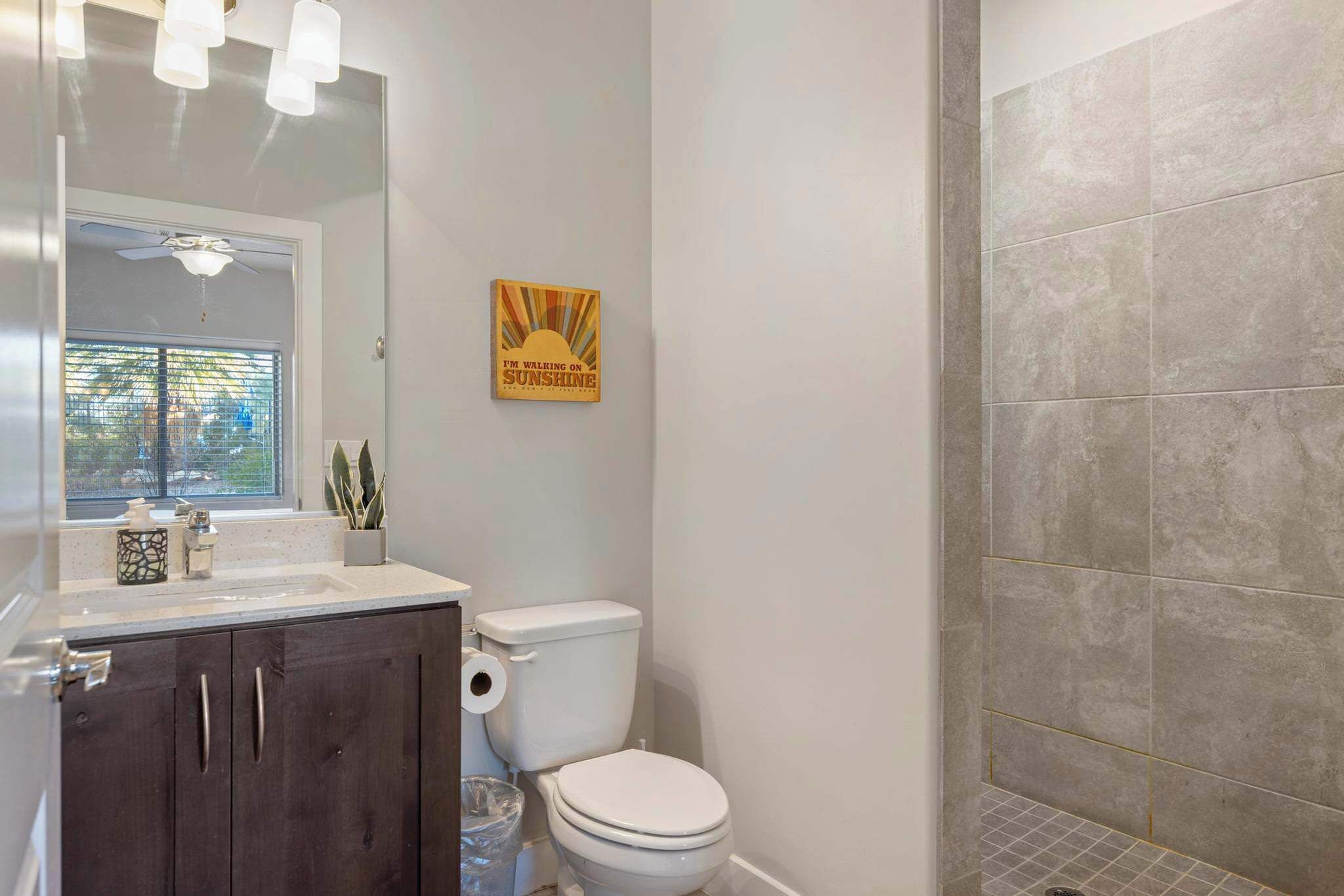 A bathroom with a toilet, a sink, a mirror, and a shower area.