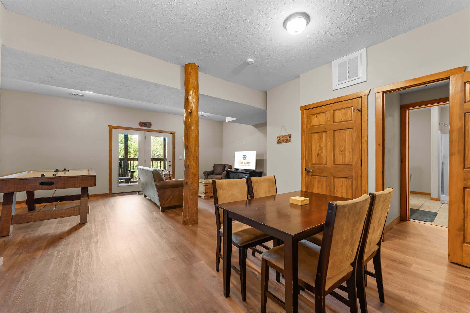 A spacious living room with a wooden dining table, comfortable seating, and a television.