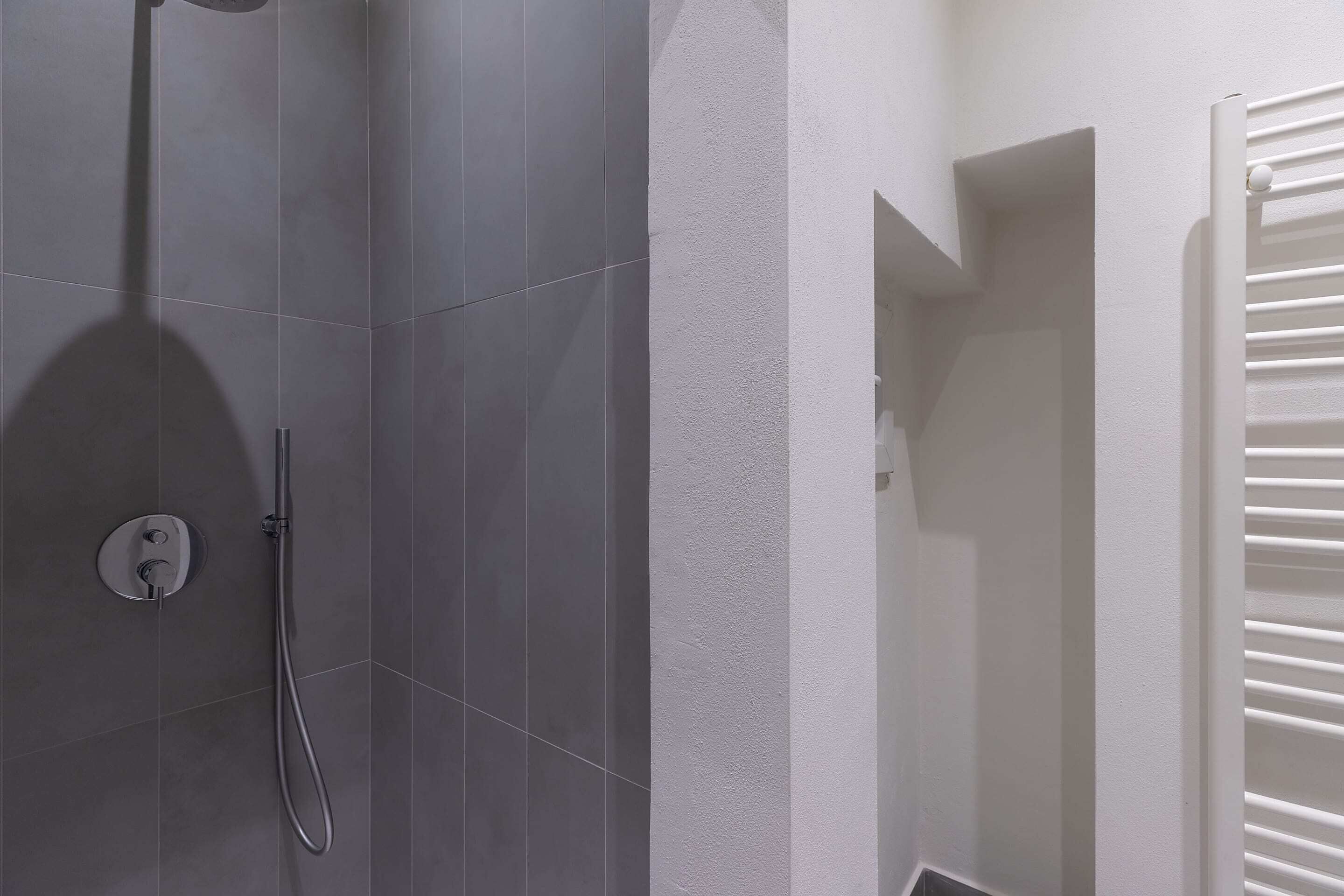 A modern bathroom with grey tiles, a white wall, and a white towel rack.