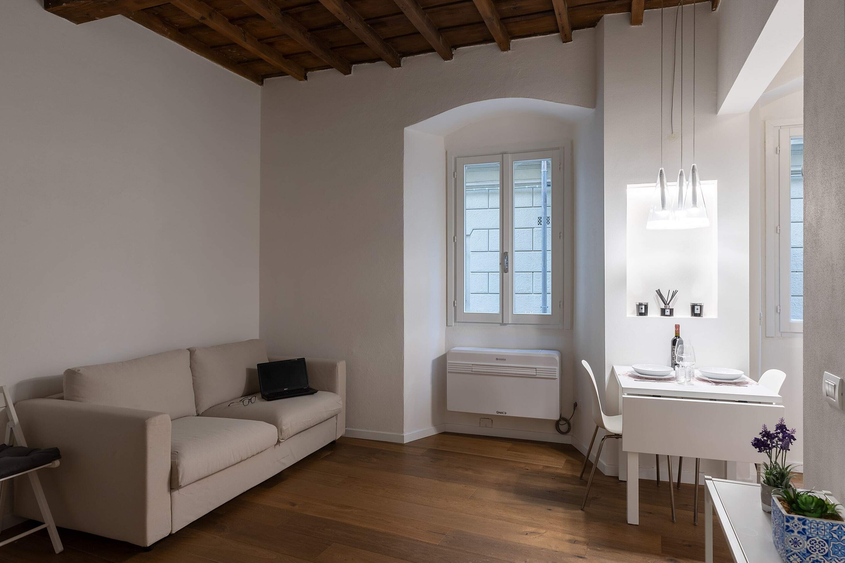 A modern living room with a sofa, a dining table, and a built-in air conditioner.