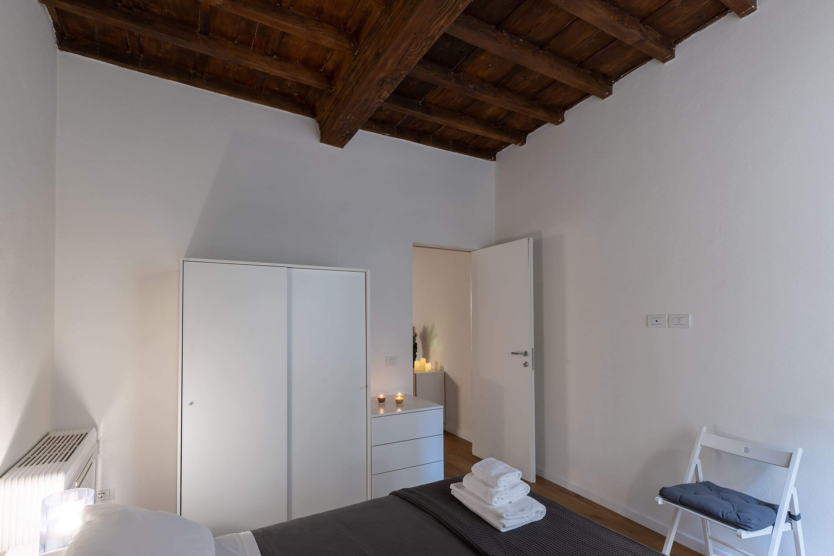 Um quarto com uma cama, uma cadeira, um guarda-roupa e uma cômoda.