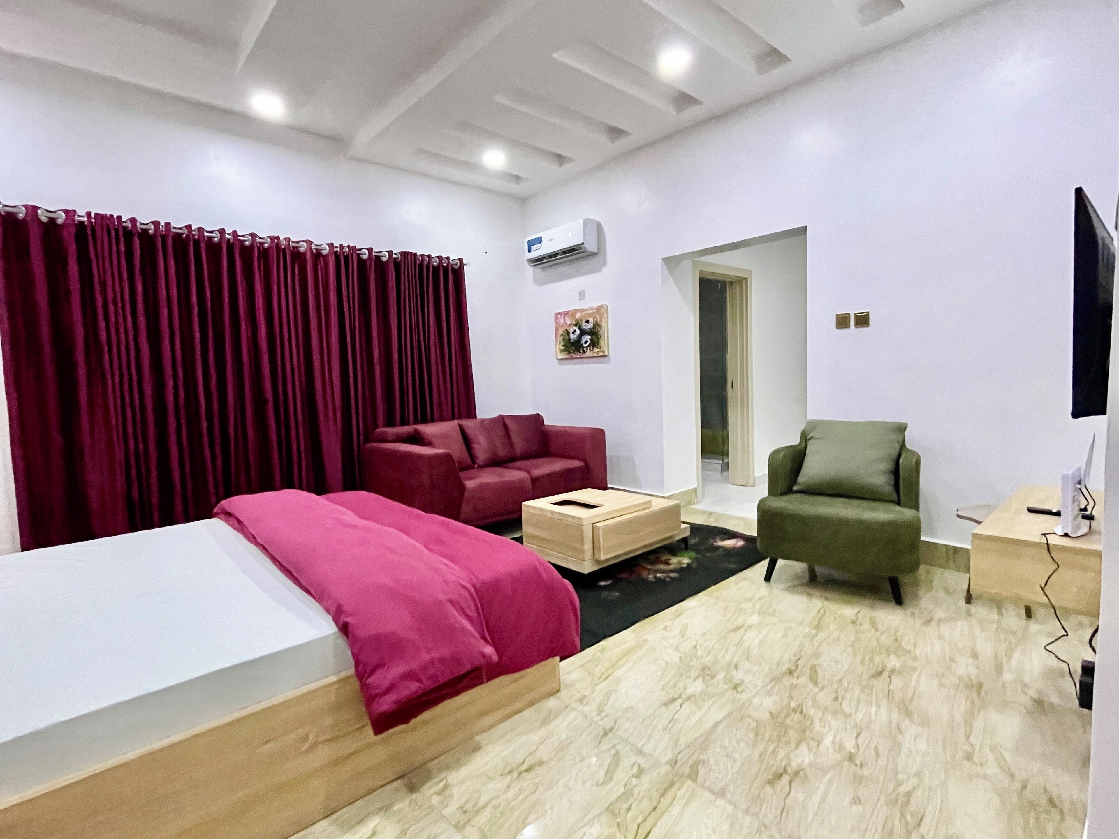 A modern room with a bed, two sofas, a small table, and a TV.