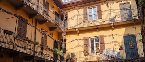A multi-story building with balconies covered in vines, wooden shutters, and a sign that reads "PORTINATA."