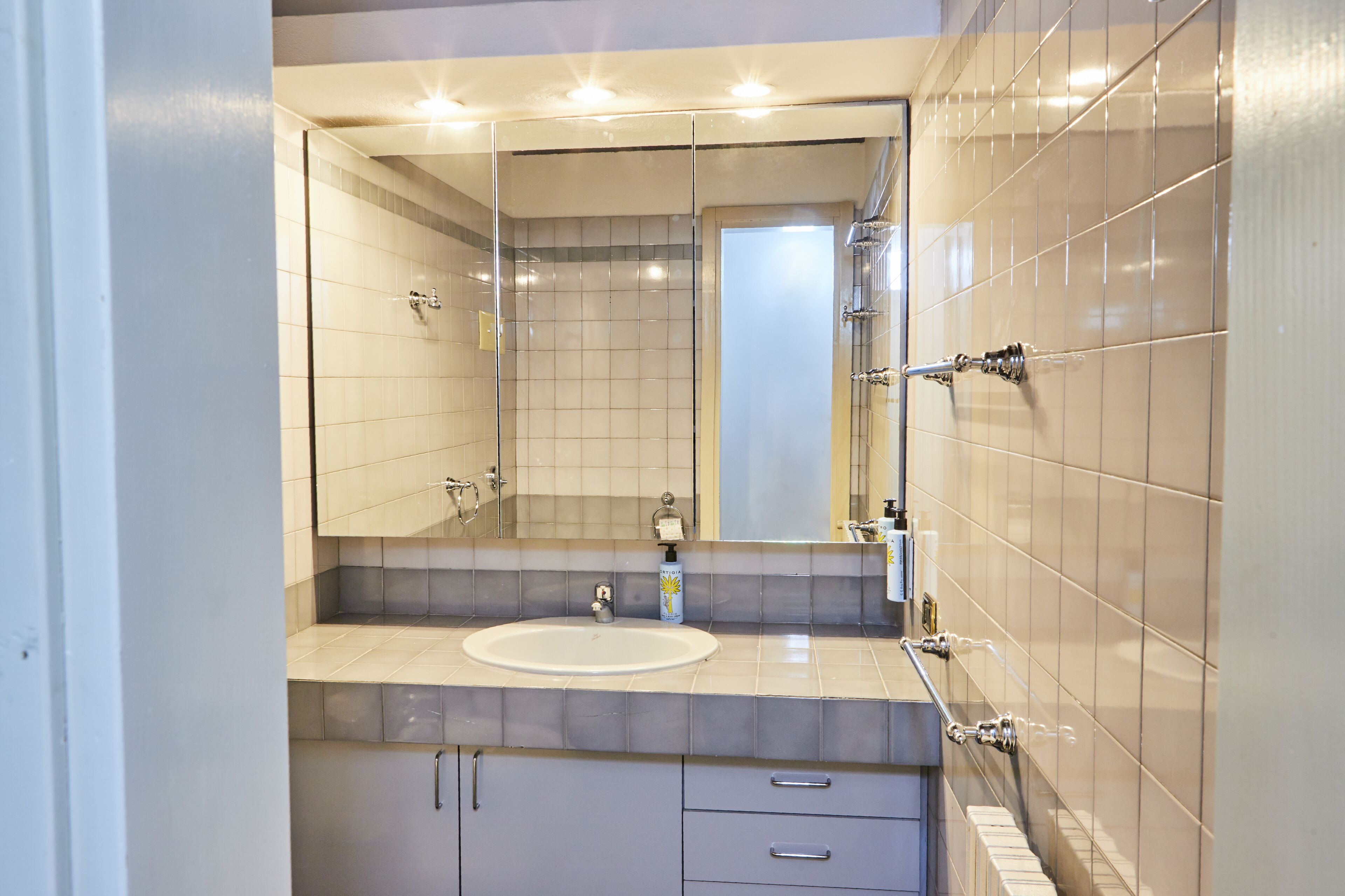 A modern bathroom with a large mirror, a sink, and a shower area.