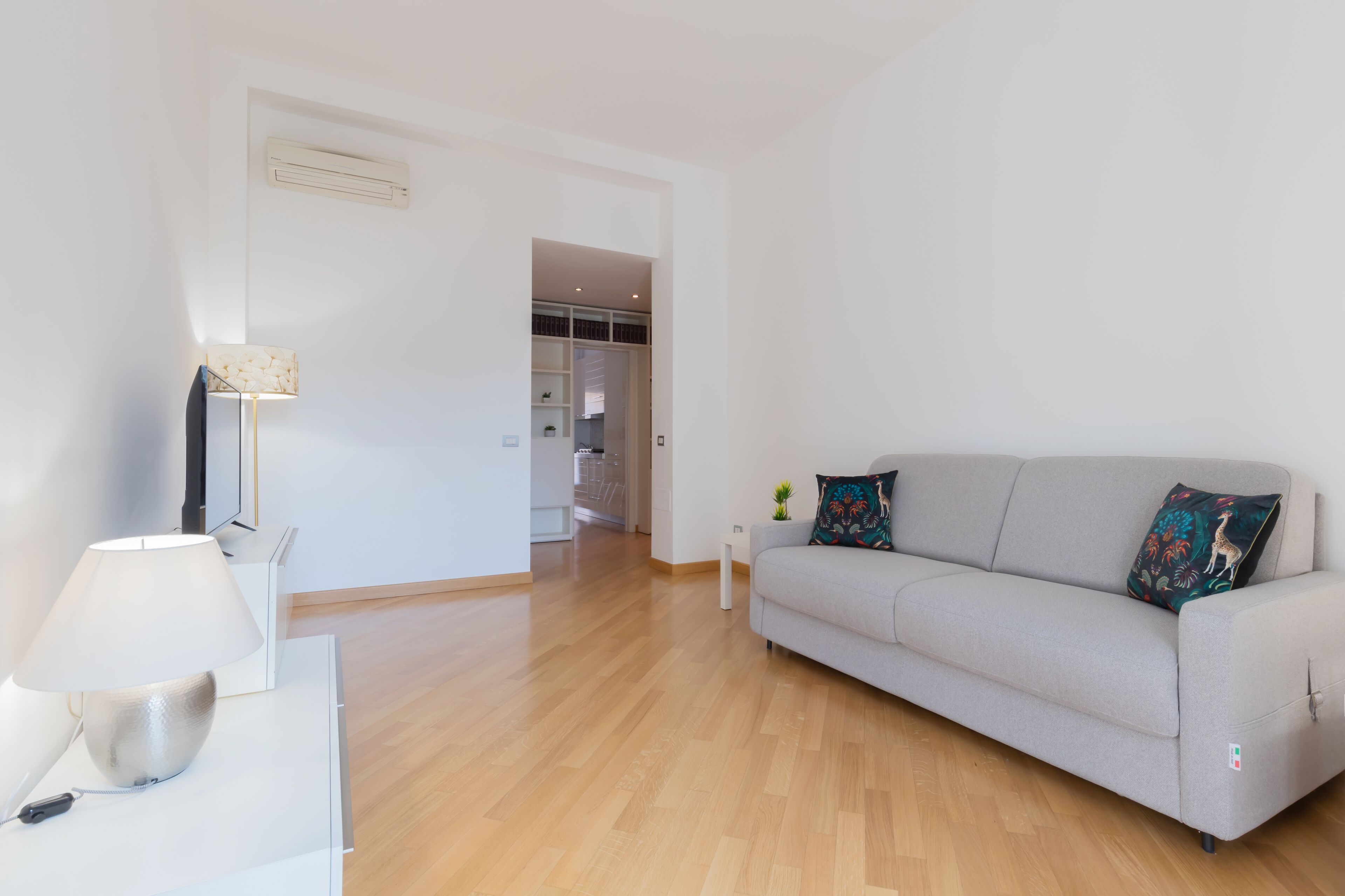 A modern living room with a sofa, a lamp, and a small table.
