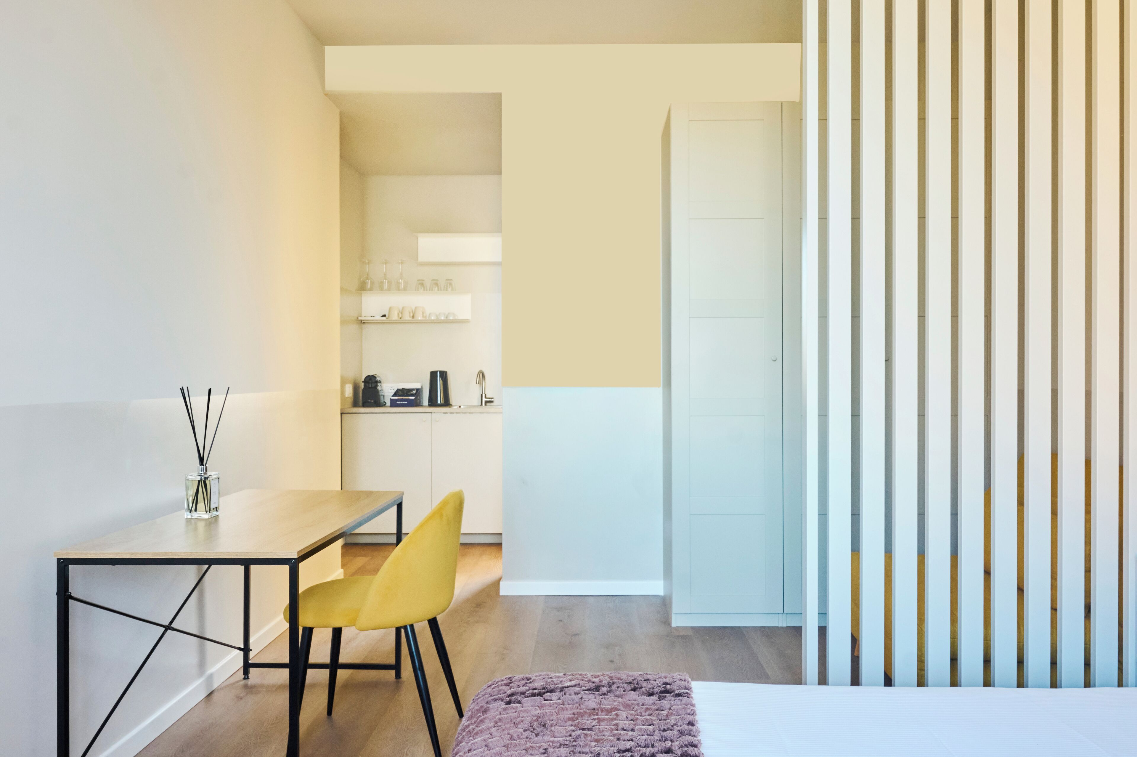 A modern room with a dining table, yellow chair, and a bed with a white headboard.