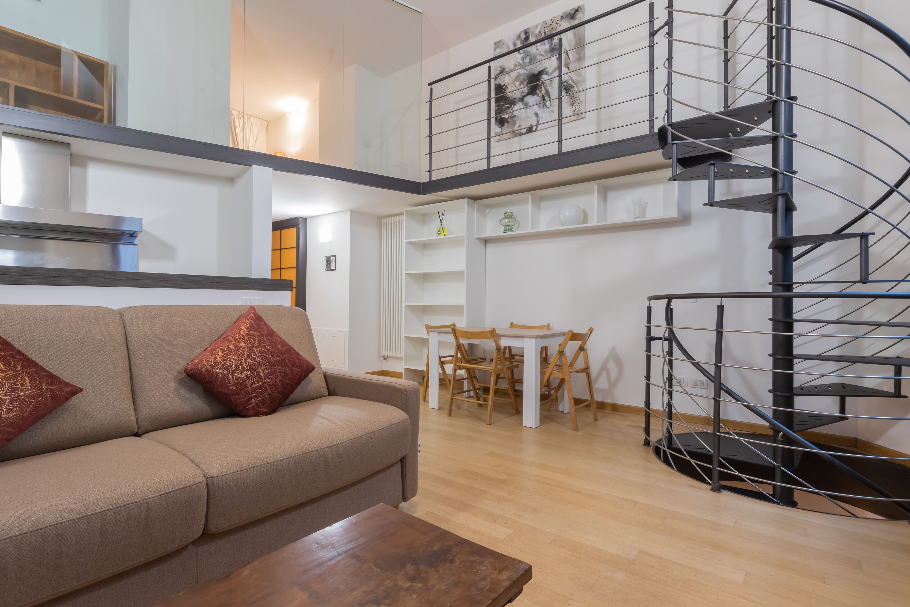 Ein modernes Wohnzimmer mit Sofa, Couchtisch, Essbereich und einer Wendeltreppe.
