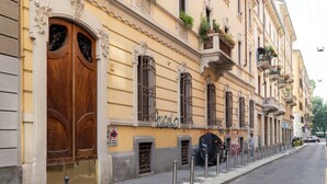 A building with ornate wooden doors and windows, a sidewalk, and a parked car. - Milan Retreats Navigli (Milan)
