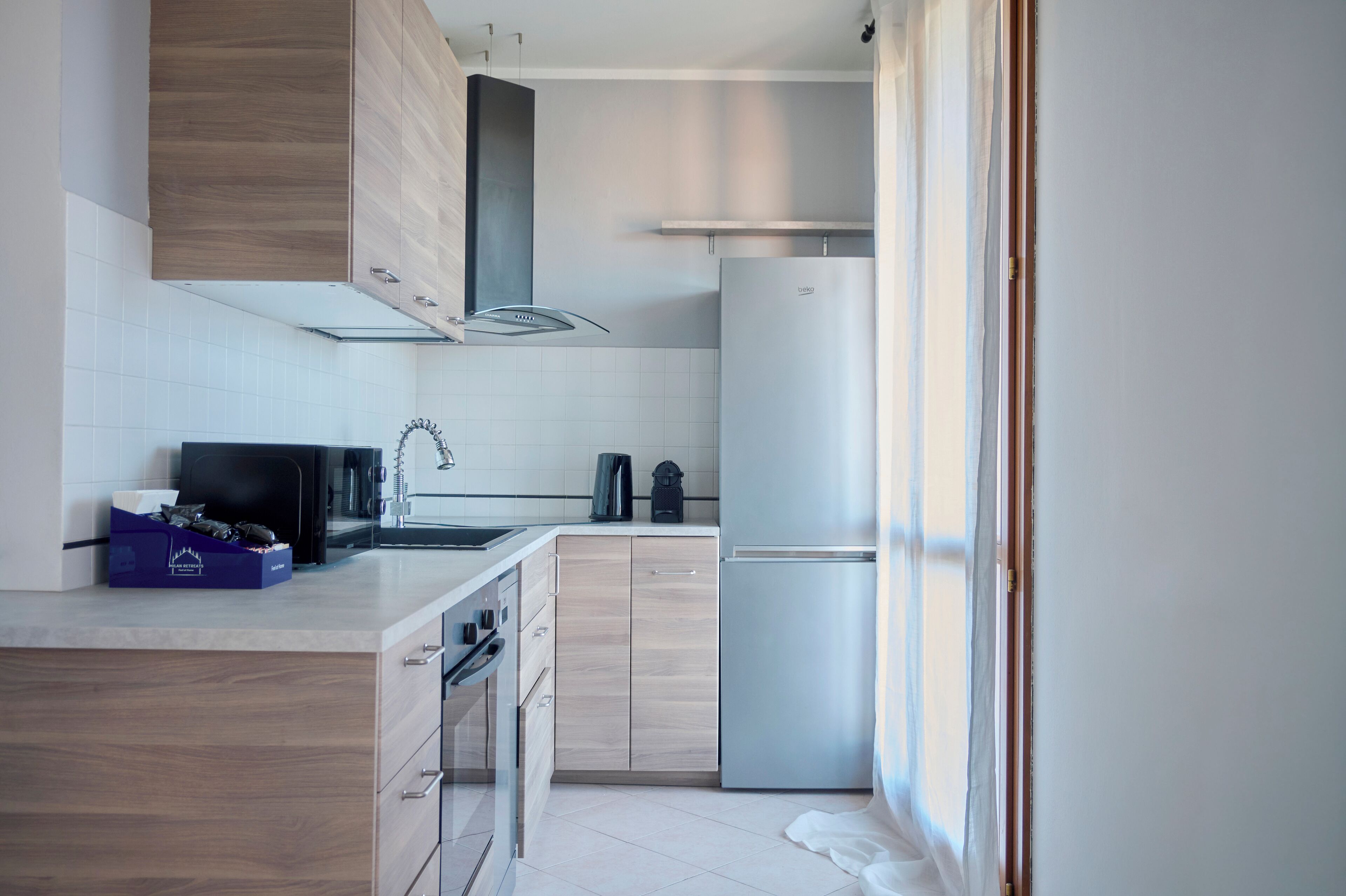 Une cuisine moderne avec des meubles en bois, un réfrigérateur en acier inoxydable et un four à micro-ondes.