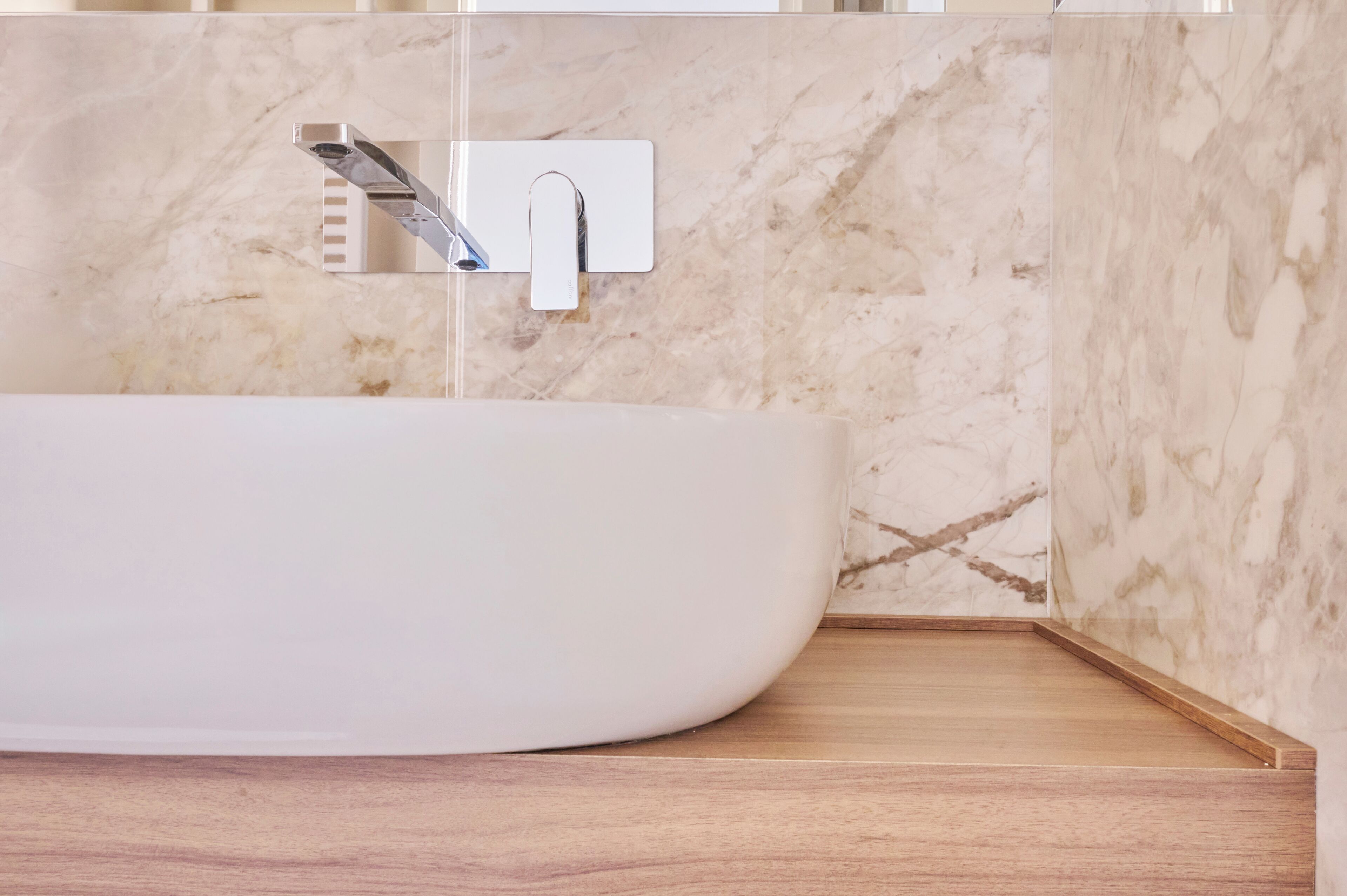 Ein modernes Badezimmer mit freistehender Badewanne, einem wandmontierten Wasserhahn und einer Marmor-Spritzschutzwand.