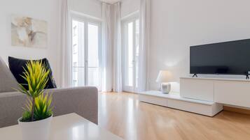 Una sala de estar moderna con un televisor de pantalla plana, un sofá, una mesita de centro y una planta en maceta.