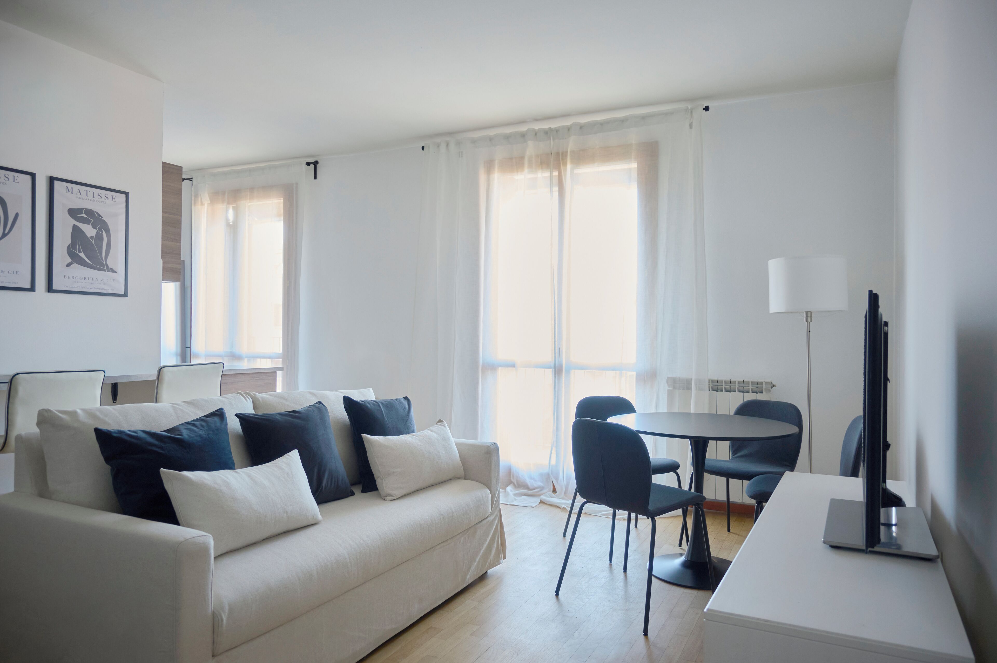 Een moderne woonkamer met een bank, stoelen, een tafel en een lamp.