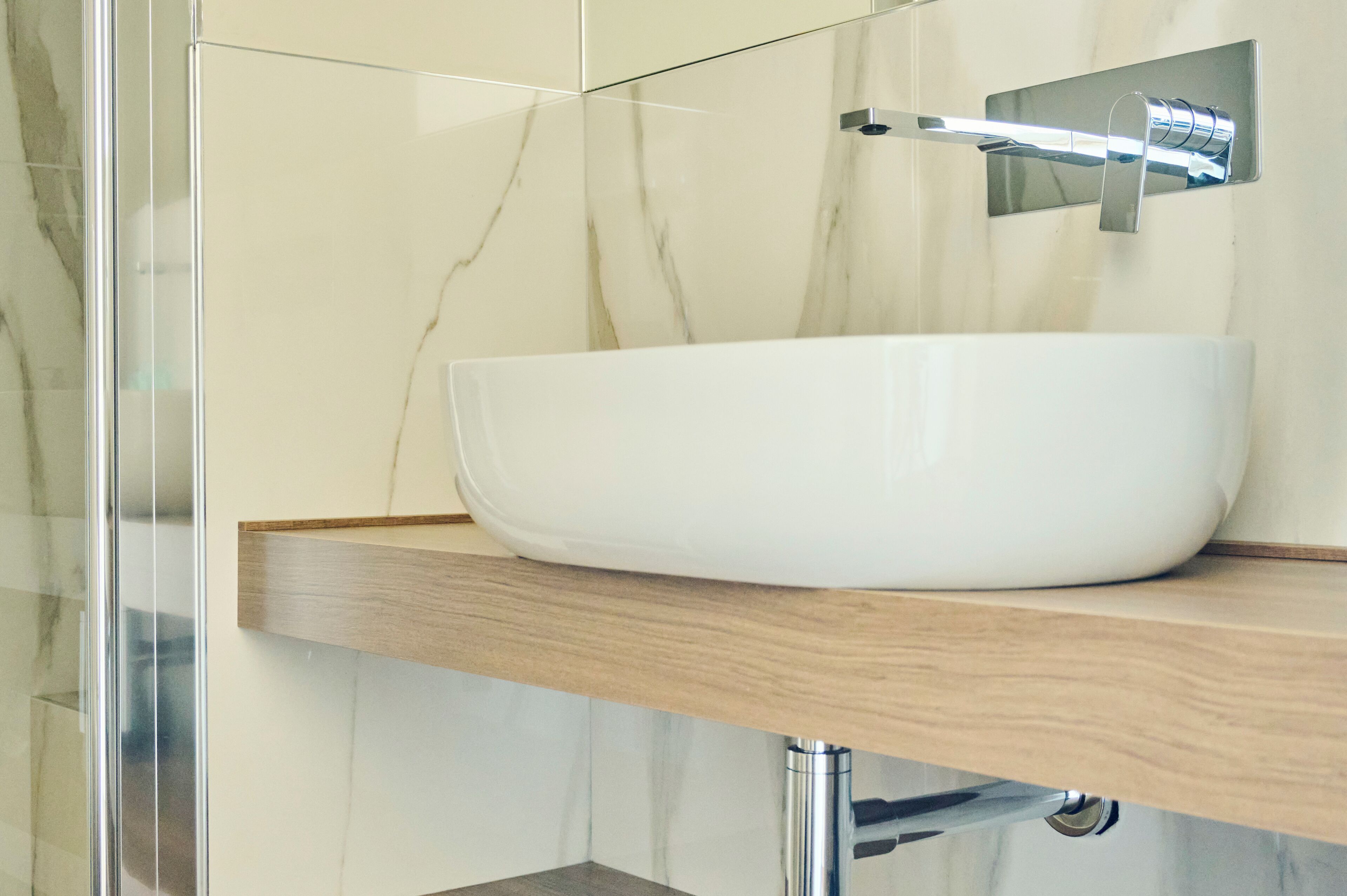 Un baño con un lavamanos tipo cuenco blanco, encimera de madera y grifo cromado.