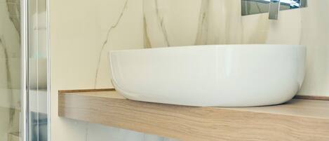 Un baño con un lavamanos tipo cuenco blanco, encimera de madera y grifo cromado.
