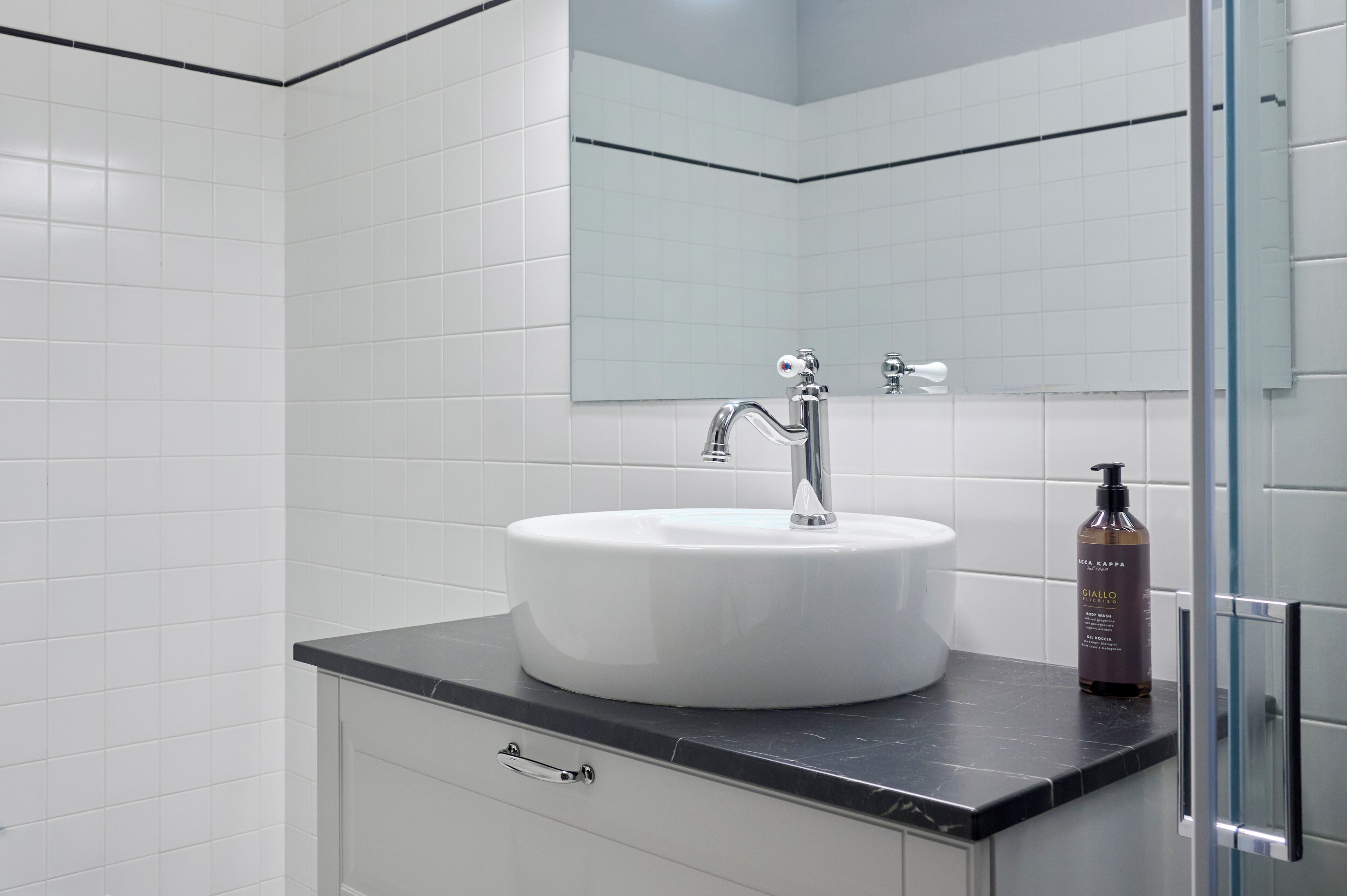 Une salle de bain avec un lavabo blanc, un miroir et une cabine de douche en verre.