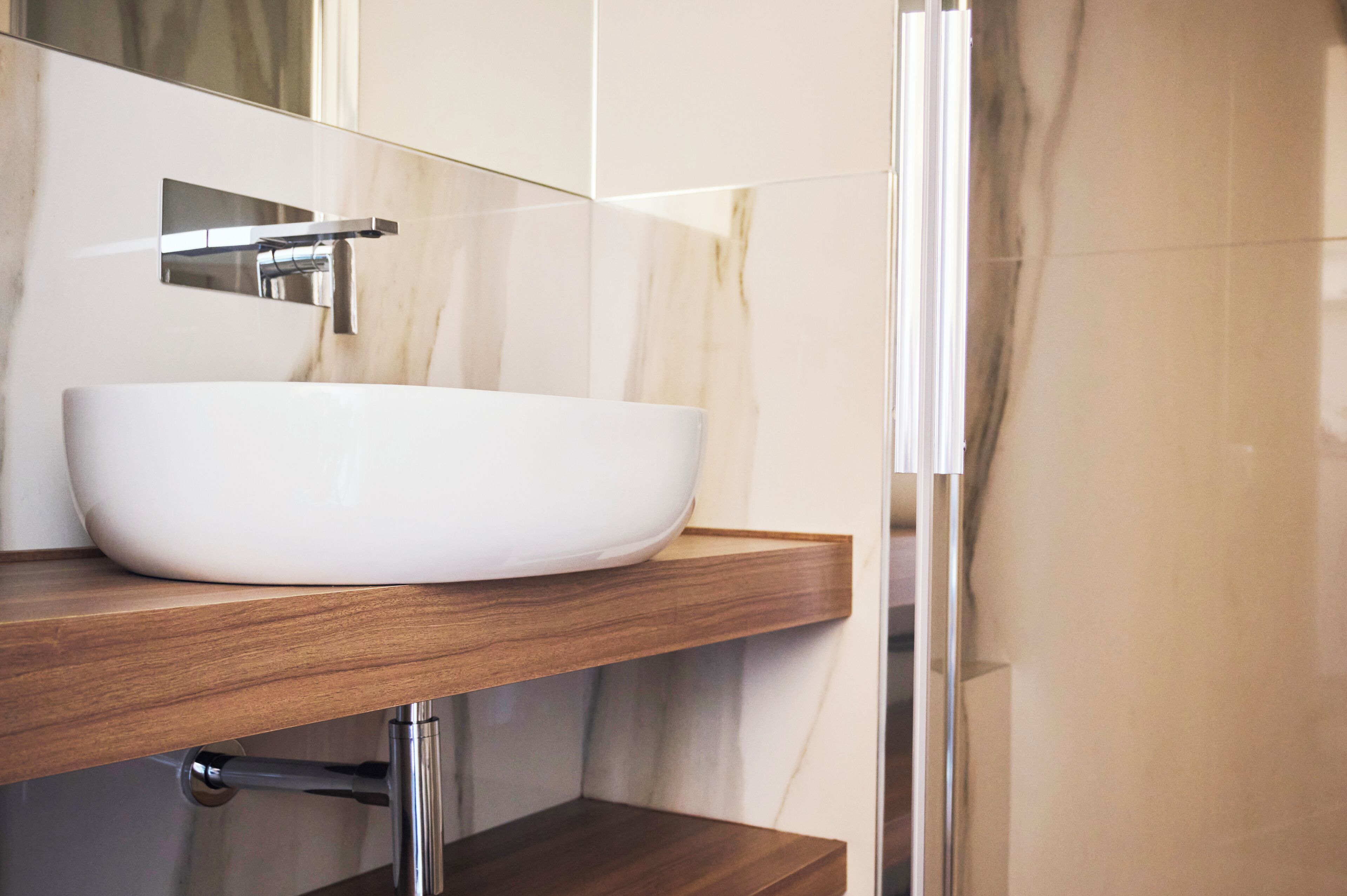 Een badkamer met een wit wastafel, een houten aanrechtblad en een douchecabine van glas.