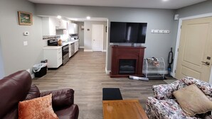 A living room with a brown leather sofa, a floral sofa, a wooden coffee table, and a TV on a stand.