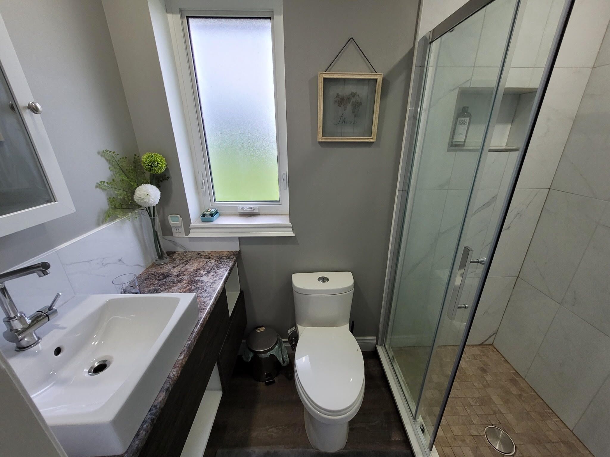 Een badkamer met een wastafel, toilet en een raam met gezandstraald glas.