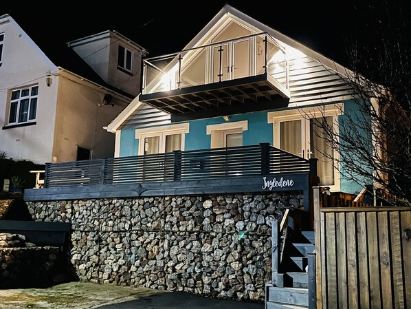 A two-story house with a stone wall and a wooden fence. - Ingledene (Brixham)