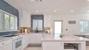 Una cocina moderna con armarios blancos, una isla central y horno empotrado.