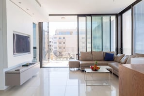 Uma sala de estar moderna com um sofá, uma mesa de centro e uma TV fixada na parede.