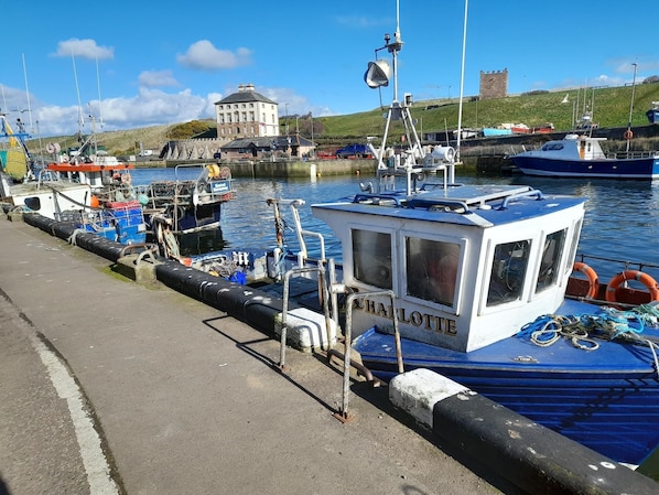 A harbor with boats docked, a small white cabin labeled "CHARLOTTE," and a building in the background. - Charming Eyemouth 1-bed Apt, Sleeps 2 Near Beach (Eyemouth)