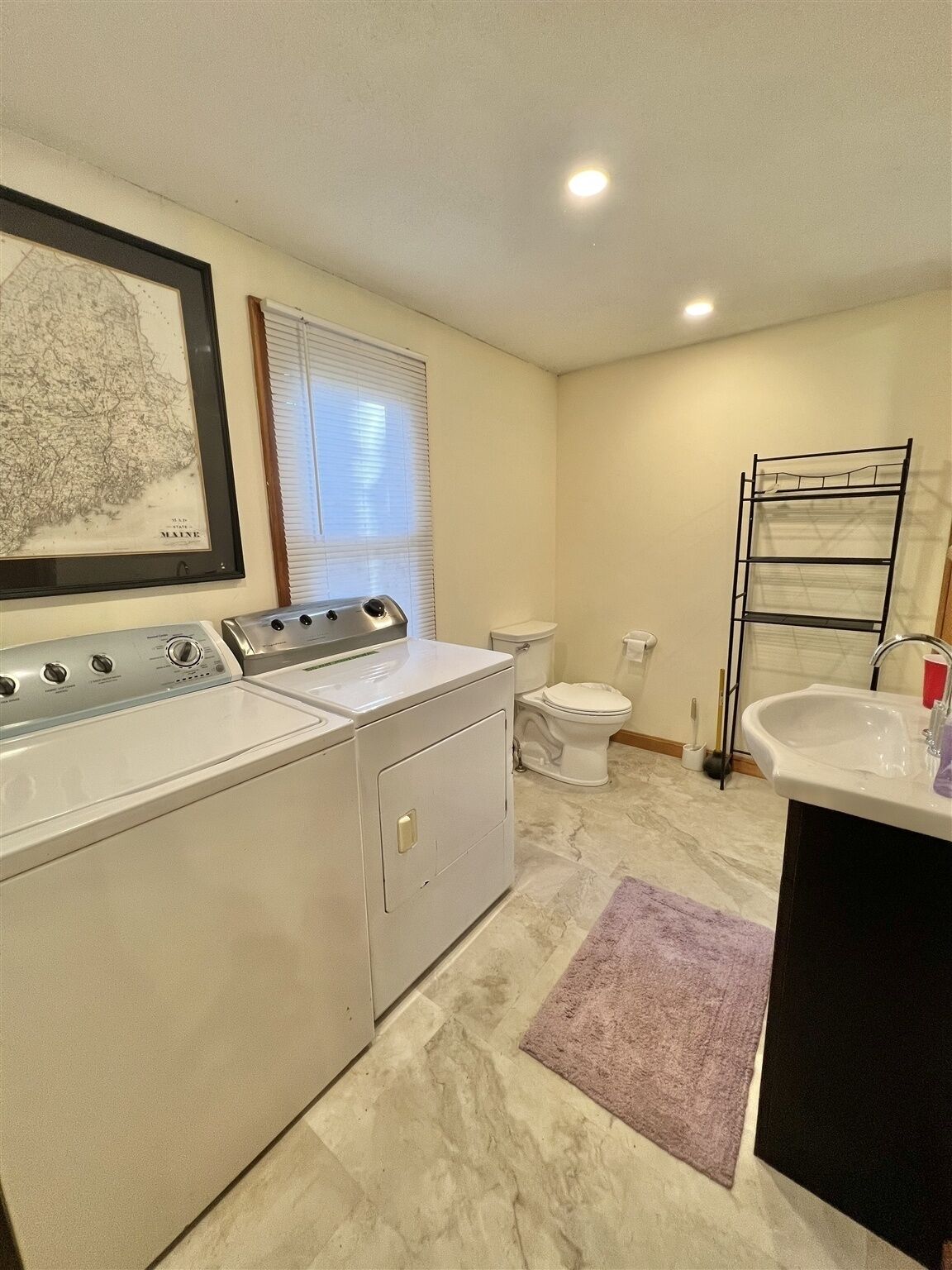 A laundry room with a washer and dryer, a toilet, and a sink.