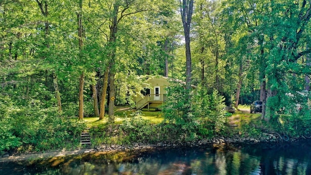 A cabin surrounded by dense forest, a small dock, and a clear reflection in the water. - Crooked River Cottage Limit 5 2 Bedroom Cottage by RedAwning (Casco)