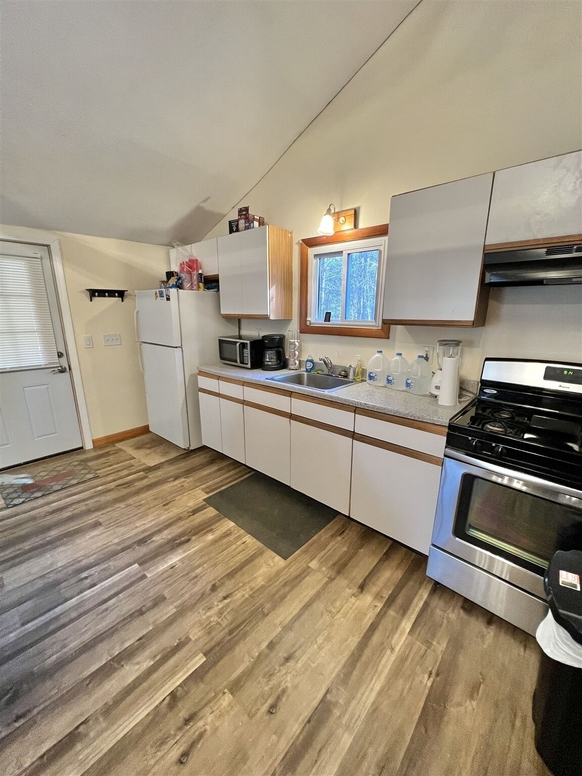 A compact kitchen with a refrigerator, microwave, stove, and sink.