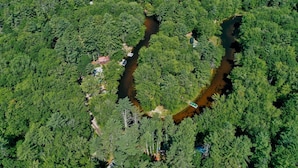 An aerial view of a dense forest with a winding river. - Crooked River Cottage Limit 5 2 Bedroom Cottage by RedAwning (Casco)