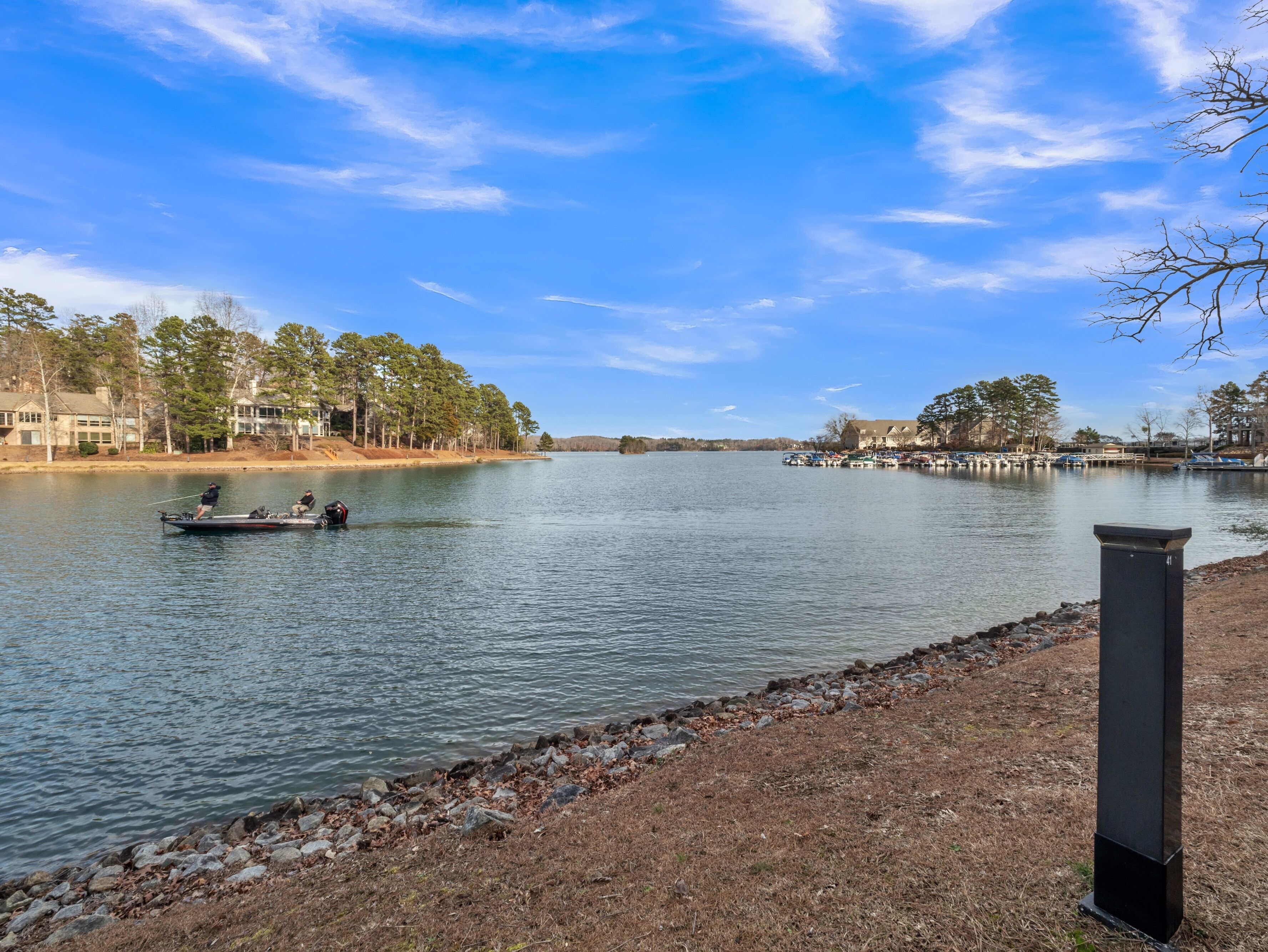 A calm lake with boats, a dock, and buildings in the background.