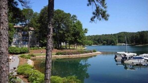 Un lago con barcos amarrados, rodeado de árboles y un edificio con balcones.