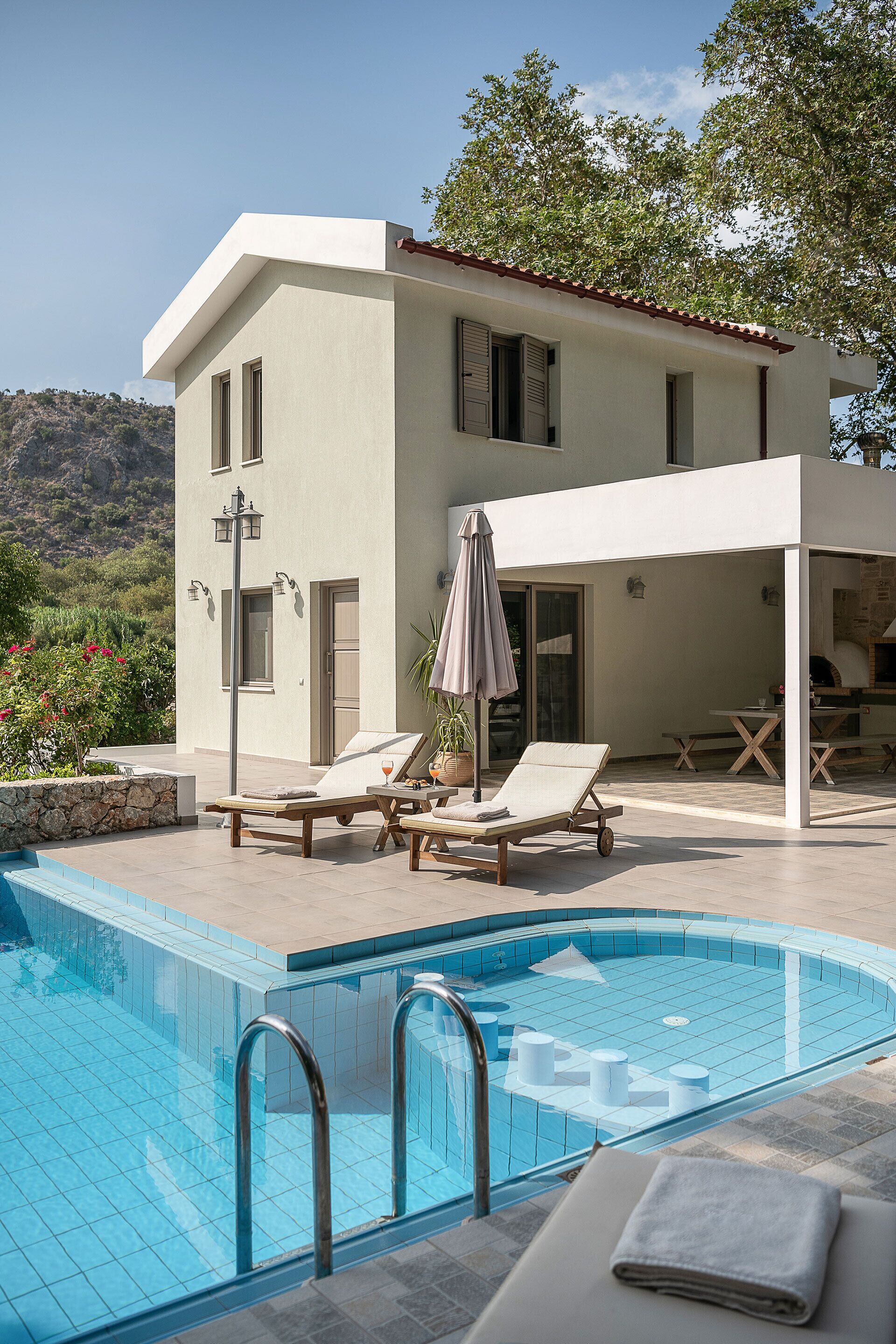 Una villa moderna con piscina, mobiliario exterior y vistas a las colinas.