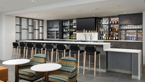 Zona de bar moderna amb un comptador llarg, diverses solles i una varietat de garrafes i vasos de licors.