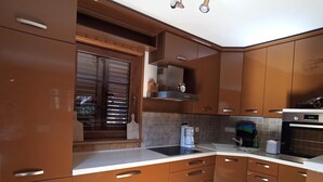 Une cuisine moderne avec des meubles en bois, un four encastré et une fenêtre équipée de stores.