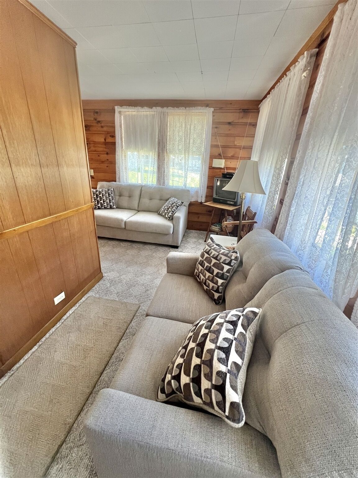 A living room with a sofa set, a television, and a lamp.