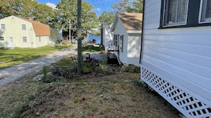 Um bairro residencial com duas casas, uma entrada de automóveis de cascalho e um poste de eletricidade com fios aéreos.