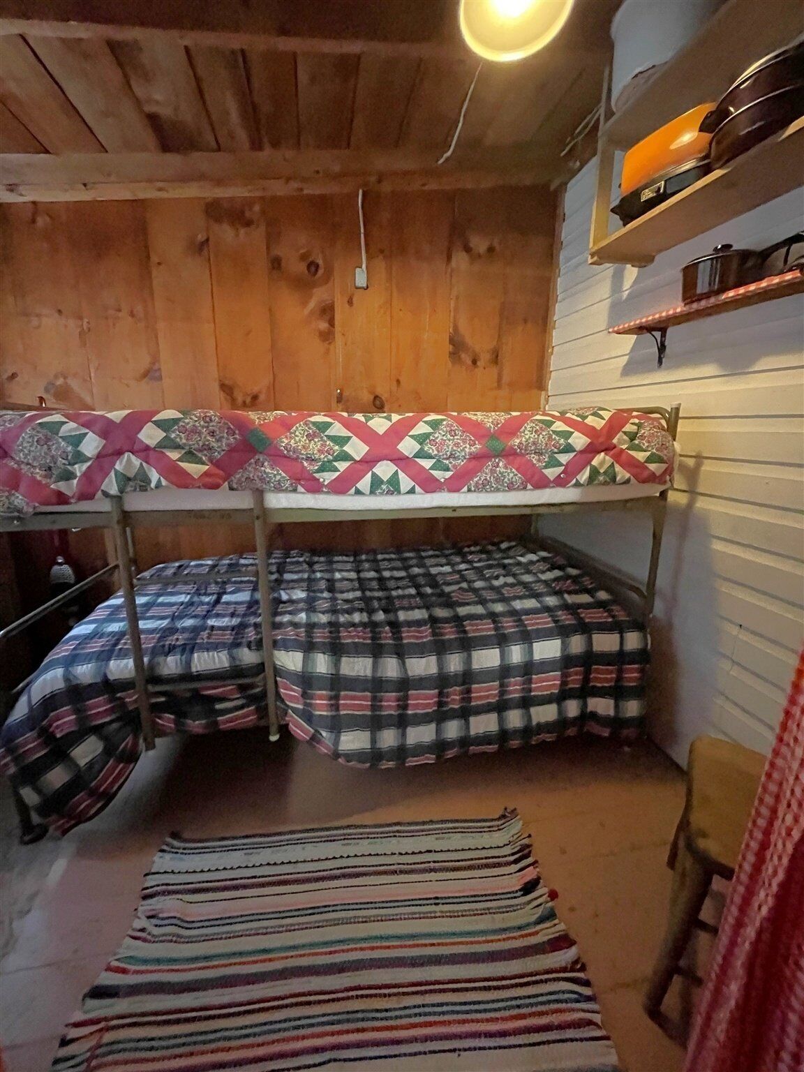 Una camera con letto a castello, soffitto in legno e ripiano con una radio.