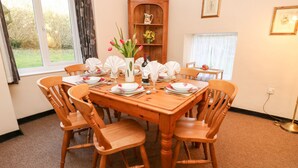 Une salle à manger avec une table en bois dressée pour quatre personnes, entourée de chaises assorties.