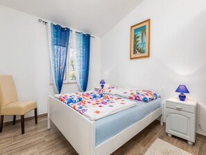 A bedroom with a bed, a chair, a nightstand, and a painting on the wall. - Villa Ketty (Fazana)