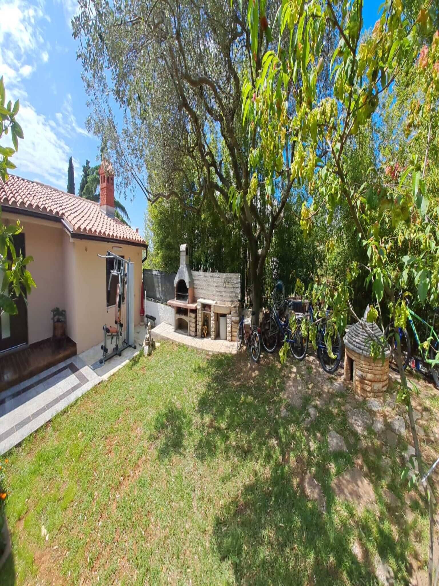 A house with a patio, a stone oven, and bicycles parked outside.