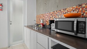 A modern kitchen with a stainless steel microwave, a coffee maker, and a bowl on the counter. - Puerto Rico Beachside Rental w Pool Otium Rentals (San Juan)