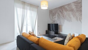 A modern living room with a sofa, a TV, and a wall with a leaf pattern. - Italianway - Brianza 14 A (Milan)