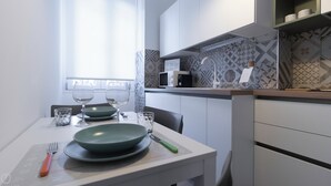 A modern kitchen with white cabinets, a microwave, and patterned backsplash. - Italianway - Brianza 14 A (Milan)
