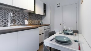 A modern kitchen with white cabinetry, a patterned backsplash, and a dining area with a table set for two. - Italianway - Brianza 14 A (Milan)