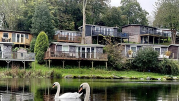 A lakeside property with multiple houses, some with balconies and others with decks. - Charming Two Bed Cottage Glan Gwna Holiday Park (Caernarfon)