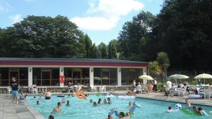 A swimming pool area with a building in the background. - Charming Two Bed Cottage Glan Gwna Holiday Park (Caernarfon)