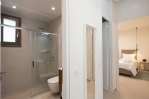 Uma casa de banho moderna com chuveiro individual com cabine de vidro, sanita e chuveiro de entrada livre.