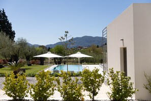Uma área de piscina com dois guarda-sóis, céu limpo e montanhas ao fundo.