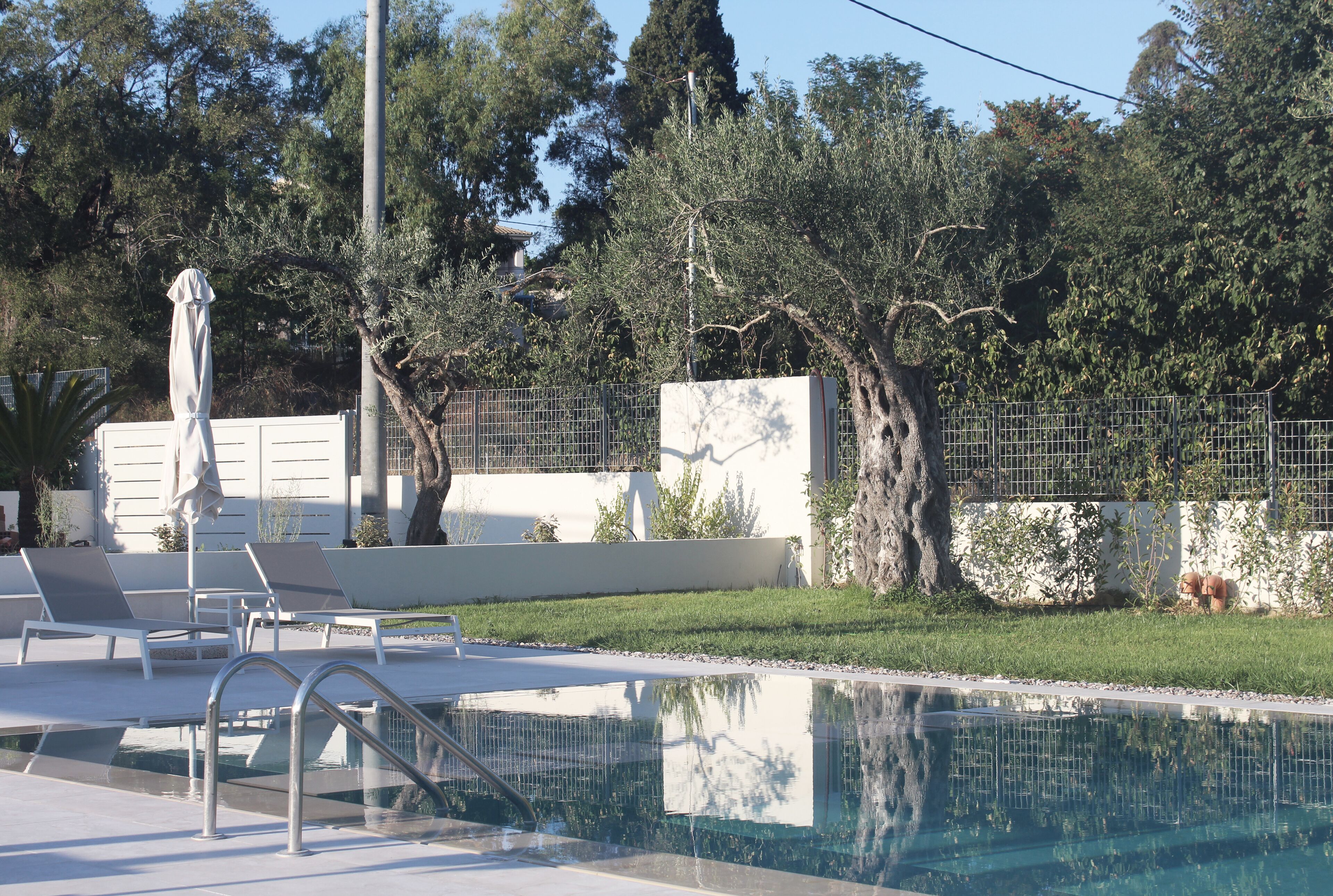 A swimming pool with lounge chairs and a fence.